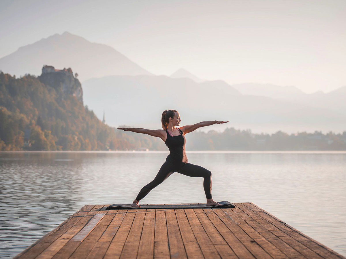 Woman doing yoga on a dock over a lake