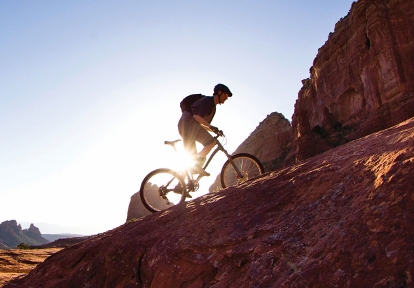 Silhouette of man riding up hill on mountain bike